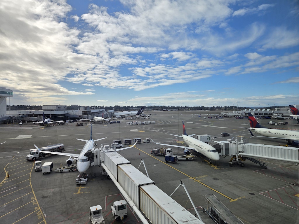 비행기, 하늘, 야외, 구름, 차량, 공항, 항공 여행, 주기장, 항공기, 지상, 비행, 여객기, 제트기, 항공사, 런웨이, 교통, 탑승교, 주차된, 항공 우주 제조업체, 항공 우주 공학, 타맥 포장, 항공기 엔진, 큰